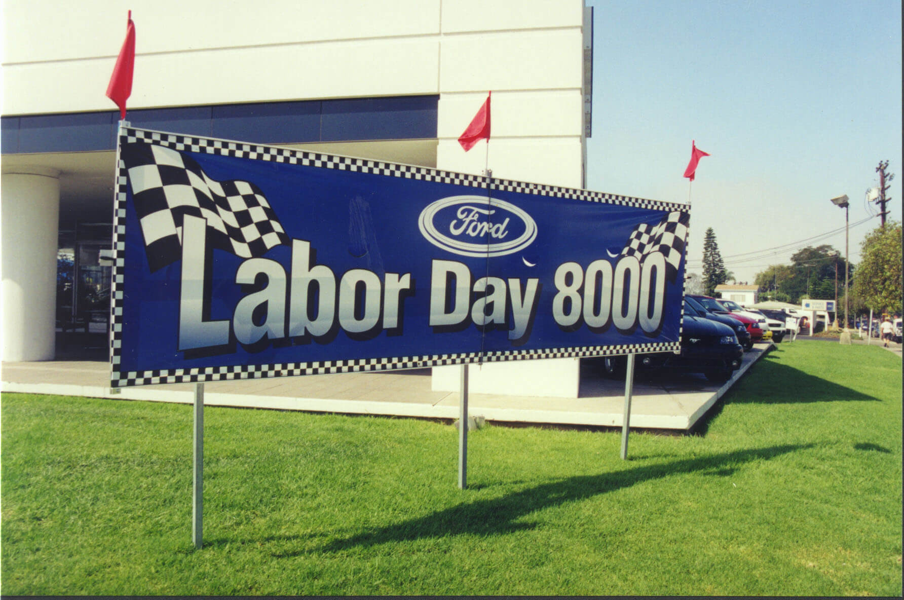 A banner being held up in banner hardware from Voxpop Marketing Systems A lawn display for outdoor marketing in a car lot from Voxpop Marketing Systems
